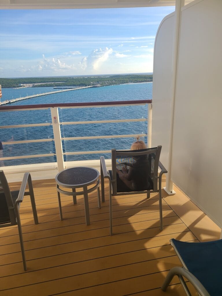 Child seated on a cruise ship balcony overlooking the water and a distant shoreline